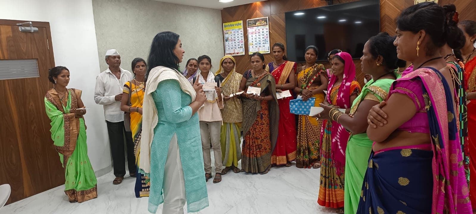 कार्यालयाच्या स्वागतकक्षात धनादेश हातात घेऊन अर्धवर्तुळात उभ्या सुमारे पंधरा महिला आणि त्यांना मार्गदर्शन करणाऱ्या फिरोजी कुर्त्यातील अधिकारी