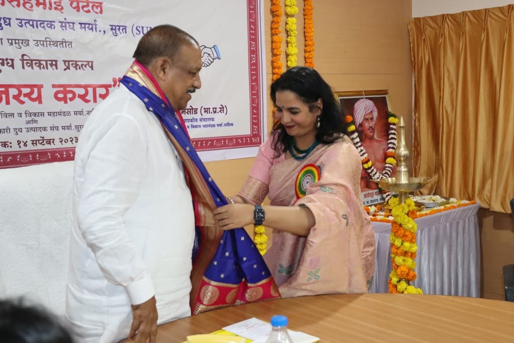 पांढऱ्या कुर्त्यातील मान्यवरांना जरीचे शाल पांघरून सन्मान करणाऱ्या गुलाबी साडीतील महिला अधिकारी; मागील फलकावर सुमुल करार व १४ सप्टेंबर २०२३ ही तारीख