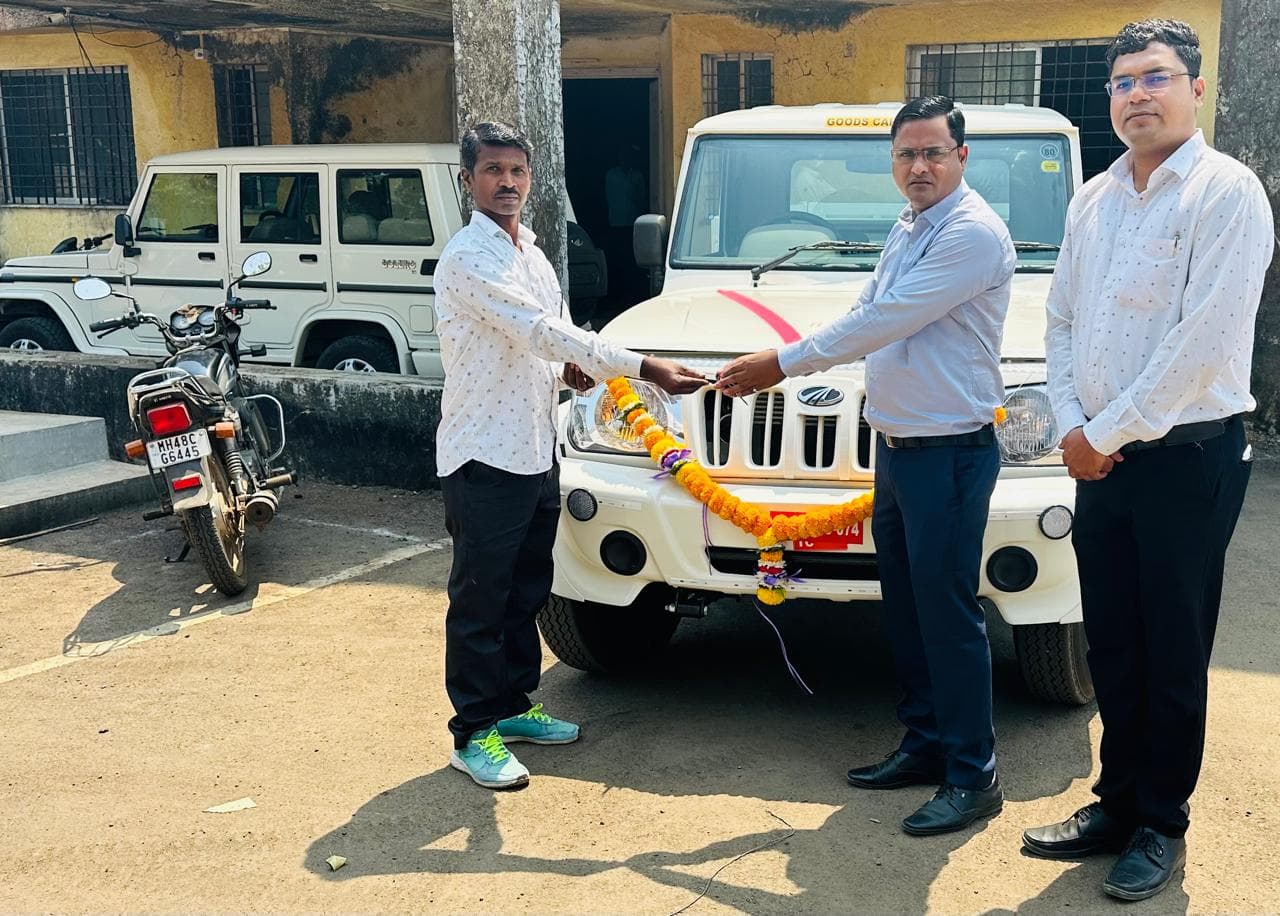 शासकीय कार्यालयासमोर झेंडूच्या माळा व लाल रिबिनीने सजवलेल्या नव्या बोलेरो पिकअपच्या बोनेटवरून लाभार्थ्याला चावी देणारे अधिकारी